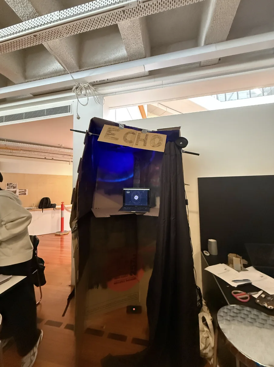 Full-size cardboard booth with blackout curtain and a laptop standing in for the screen